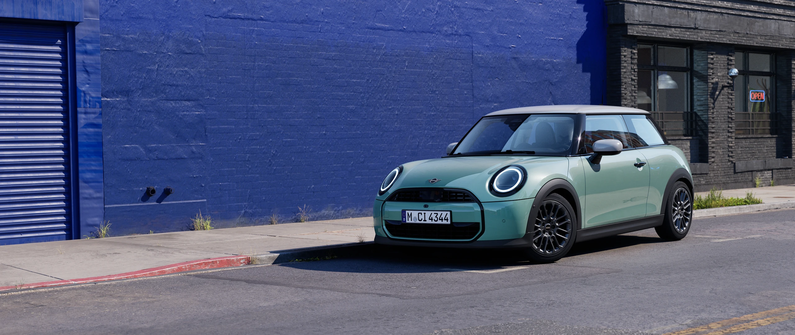 MINI Cooper stationné dans une rue urbaine à côté d’un mur bleu.