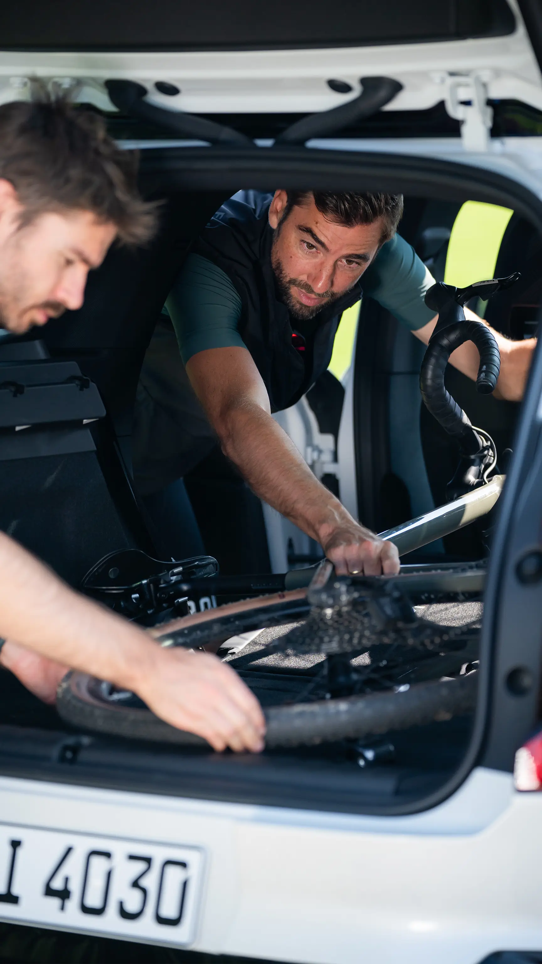 Deux personnes chargeant un vélo à l’arrière d’un véhicule MINI par le coffre ouvert.