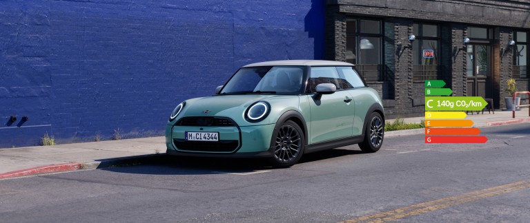 MINI Cooper stationné dans une rue urbaine à côté d’un mur bleu.