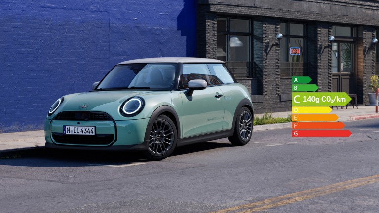 MINI Cooper stationné dans une rue urbaine à côté d’un mur bleu.